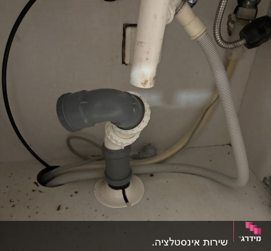 צנרת מתחת לכיור עם חיבורים וצינורות פלסטיק
